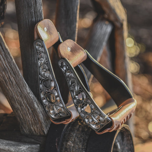 A pair of oxbows with metallic silver trim, displayed on rustic wooden props.
